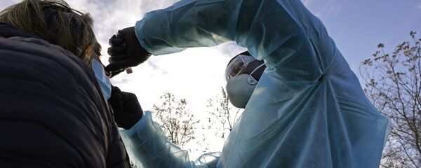 LPN Yeonis Jean Jacques administers a COVID-19 test to a woman, Thursday, Dec. 3, 2020, in Lawrence, Mass. LPN Yeonis Jean Jacques administers a COVID-19 test to a woman, Thursday, Dec. 3, 2020, in Lawrence, Mass. - Sputnik International