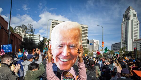 A woman holds a Joe Biden mask as people march in Los Angeles celebrating after Joe Biden was declared the winner of the 2020 presidential election on November 7, 2020. - Democrat Joe Biden has won the White House, US media said November 7, defeating Donald Trump and ending a presidency that convulsed American politics, shocked the world and left the United States more divided than at any time in decades. - Sputnik International