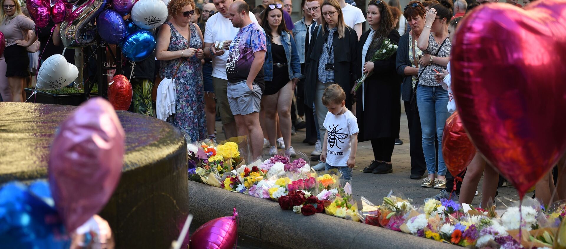 People pay their respects as they look at flowers and balloons left in central Manchester on May 22, 2018, the one year anniversary of the deadly attack at Manchester Arena.  - Sputnik International, 1920, 07.12.2020