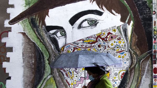 A woman wearing a face mask walks past a mural in Rome's Trastevere district on 2 December 2020 during the COVID-19 pandemic caused by the novel coronavirus - Sputnik International