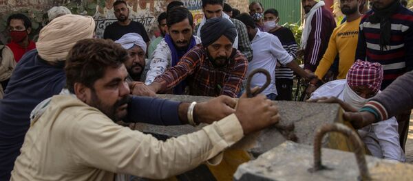 Farmers remove police barricades to reach a protest site during a nationwide strike against the newly passed farm bills at Singhu border near Delhi, India, December 8, 2020 - Sputnik International