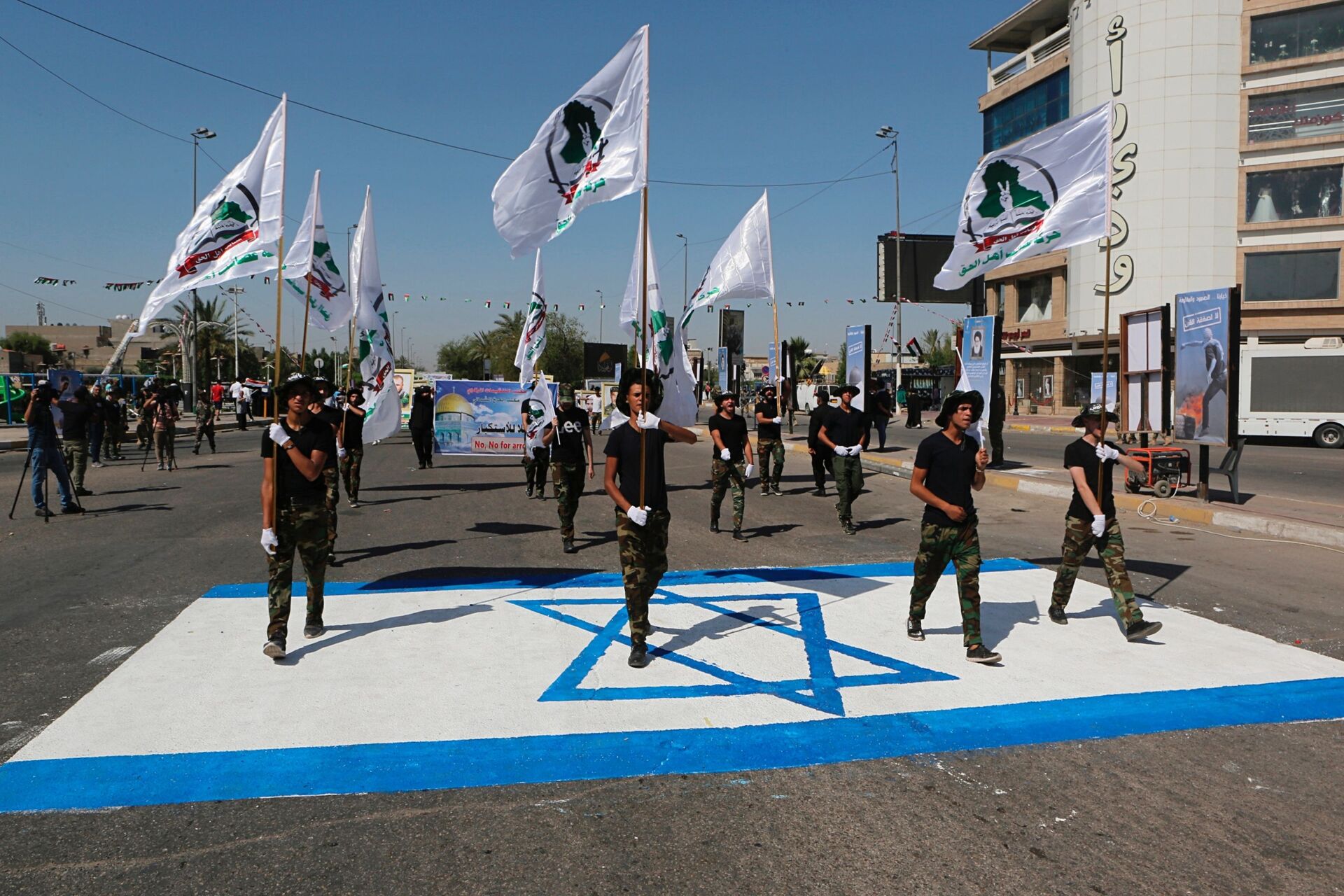 Iraq's Iranian-supported Popular Mobilization Forces militiamen marching over an Israeli flag drawn on the street in Baghdad, May 2019. - Sputnik International, 1920, 07.09.2021