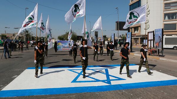 Iraq's Iranian-supported Popular Mobilization Forces militiamen marching over an Israeli flag drawn on the street in Baghdad, May 2019. - Sputnik International