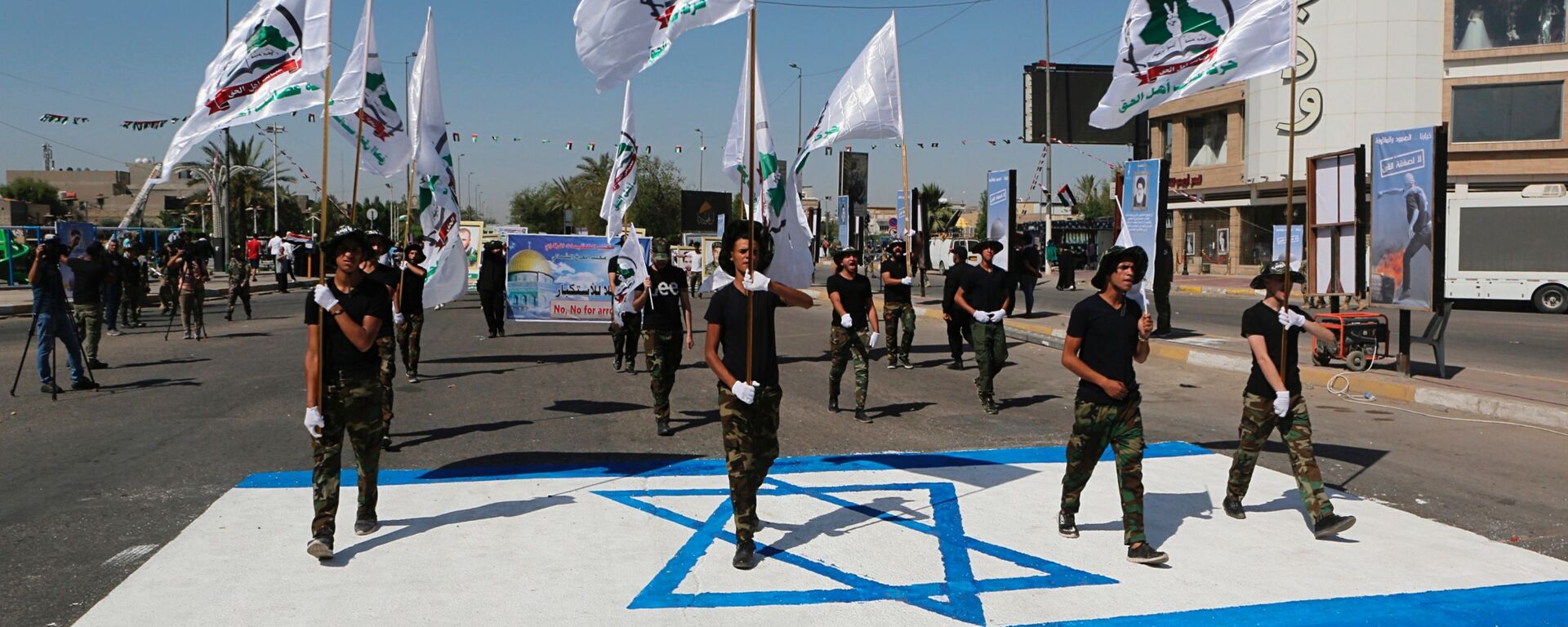 Iraq's Iranian-supported Popular Mobilization Forces militiamen marching over an Israeli flag drawn on the street in Baghdad, May 2019. - Sputnik International, 1920, 20.04.2024