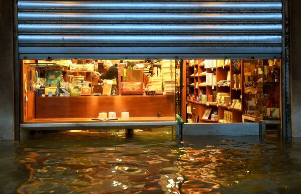 A shopkeeper tries to prevent water from getting into his shop, Venice - Sputnik International