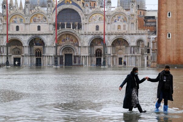 A couple walks in flooded St. Mark's Square, Venice - Sputnik International