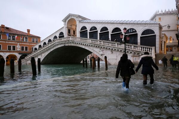 People walk along a flooded street near the Rialto Bridge, Venice - Sputnik International