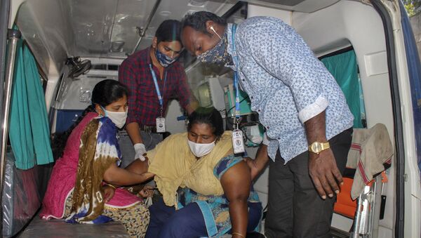 A patient is assisted by others to get down from an ambulance at the district government hospital in Eluru, Andhra Pradesh state, India, Tuesday, Dec.8, 2020 - Sputnik International