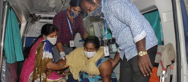 A patient is assisted by others to get down from an ambulance at the district government hospital in Eluru, Andhra Pradesh state, India, Tuesday, Dec.8, 2020 - Sputnik International