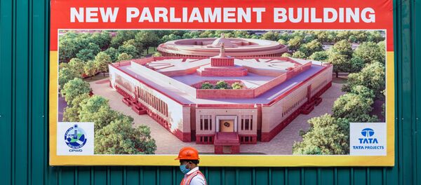 A worker walks past a banner at the boundary of the new Indian Parliament house construction site in New Delhi on December 10, 2020. A worker walks past a banner at the boundary of the new Indian Parliament house construction site in New Delhi on December 10, 2020. - Sputnik International
