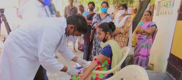 Healthcare personnel takes a blood sample from a patient during an examination, after hundreds of people were hospitalised due to an unknown illness in the southern state of Andhra Pradesh, in this still frame taken from video dated December 9, 2020 - Sputnik International