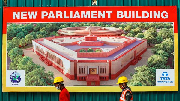 Construction workers walk past a hoarding featuring India's new parliament building outside its construction site in New Delhi, India, December 10, 2020. - Sputnik International