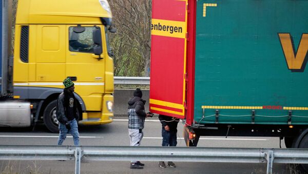 Migrants try to hide inside trucks waiting on the road in Calais - Sputnik International