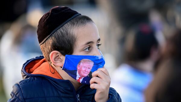 A child wears a protective face mask depicting U.S. President Trump at the 2020 annual National Chanukah Menorah Lighting near the White House in Washington - Sputnik International