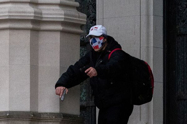 A man wearing a protective mask points his gun outside the Cathedral Church of St. John the Divine in the Manhattan borough of New York City, New York, U.S., December 13, 2020.  - Sputnik International