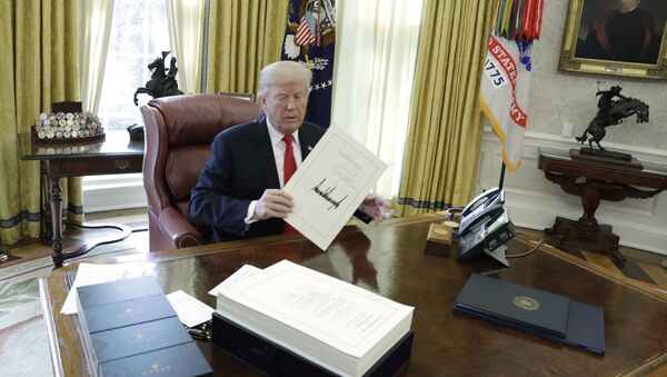 President Donald Trump displays the $1.5 trillion tax overhaul package he had just signed, Friday, Dec. 22, 2017, in the Oval Office of the White House in Washington. The bill provides generous tax cuts for corporations and the wealthiest Americans, plus smaller cuts for middle- and low-income families. - Sputnik International