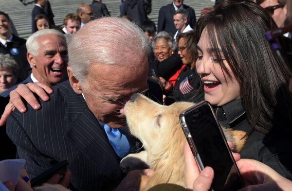 Former Vice President Joe Biden gets a kiss from a dog as he greets the crowd on Capitol Hill in Washington on 22 March, 2017 following an event marking seven years since former President Barack Obama signed the Affordable Care Act into law. - Sputnik International