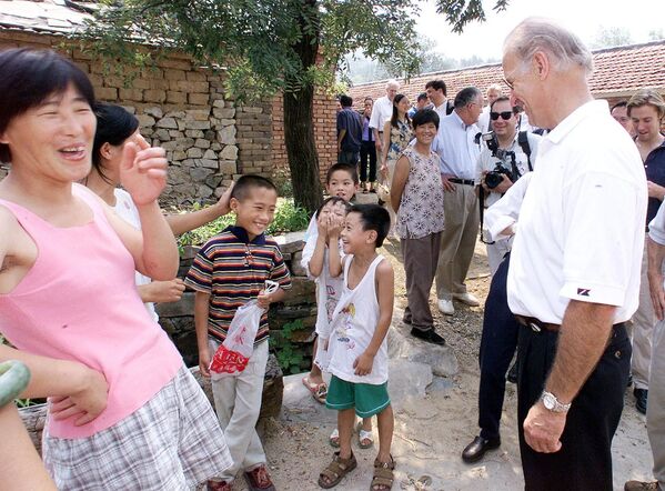 Villagers laugh as US Senate Foreign Relations Committee Chairman Joseph Biden (R) proclaims nine-year-old Gao Shan (3rd L-in the striped shirt) as the future president of China, during a visit to the village of Yanzikou, north of Beijing on 10 August, 2001.  - Sputnik International