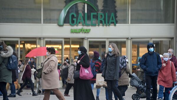 Shoppers and pedestrians wearing face masks walk across Alexanderplatz in front of the Galeria Kaufhaus department store in the centre of Berlin on December 14, 2020, a few days ahead of a partial lockdown to curb the spread of the ongoing novel coronavirus (Covid-19) pandemic.  - Sputnik International