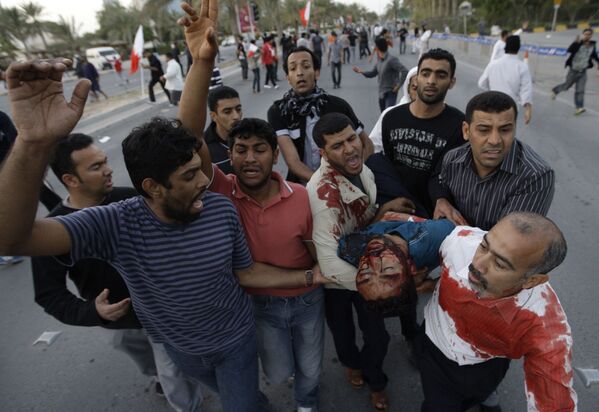 An unidentified Bahraini anti-government protester is carried to a vehicle to be taken to hospital after being wounded during a demonstration in Manama, Bahrain, Friday, 18 February 2011 - Sputnik International