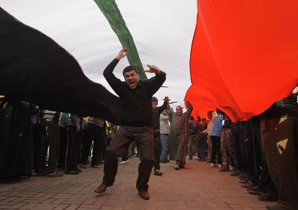 Protesters chant anti-Iraqi government slogans under a huge Iraqi flag during a protest in Tahrir Square in Baghdad, Iraq, Wednesday, 23 February 2011 - Sputnik International