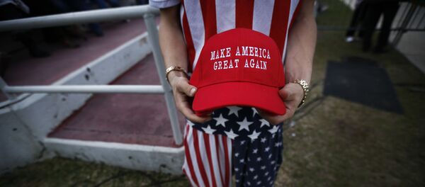 A man dressed in American flag clothes holds Make America Great Again hats before President-elect Donald Trump speaks at a rally at the Ladd–Peebles Stadium, Saturday, Dec. 17, 2016, in Mobile, Ala - Sputnik International