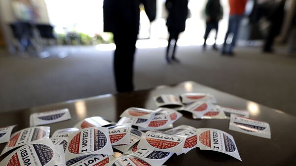 In this March 17, 2020, file photo I Voted stickers sit on the table for voters at Trinity Lutheran Church in Evanston, Ill. The U.S. intelligence community has warned over and over that foreign adversaries can and will interfere in the 2020 presidential election.  Just six weeks before the first ballots are cast, the threat has never been higher, and there are new signs that the nation’s electoral system is already under attack. - Sputnik International