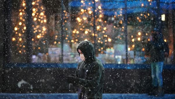 A person wearing a protective face mask walks as snow begins to fall in Times Square during a Nor'easter, during the coronavirus disease (COVID-19) pandemic in the Manhattan borough of New York City, New York, U.S., December 16, 2020 - Sputnik International