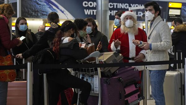 Travellers, one dressed in a Father Christmas outfit and all wearing face coverings, queue with their luggage in the departures hall at Terminal 2 of Heathrow Airport in west London on December 21, 2020, as a string of countries around the world banned travellers arriving from the UK, due to the rapid spread of a new, more-infectious coronavirus strain. - Sputnik International