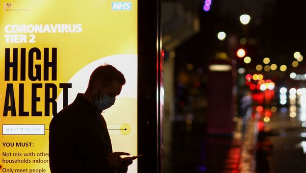 A man wearing a protective mask uses a phone at a bus stop, amidst the spread of the coronavirus disease (COVID-19), in London, Britain December 3, 2020 - Sputnik International