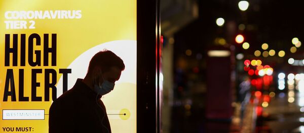 A man wearing a protective mask uses a phone at a bus stop, amidst the spread of the coronavirus disease (COVID-19), in London, Britain December 3, 2020 - Sputnik International