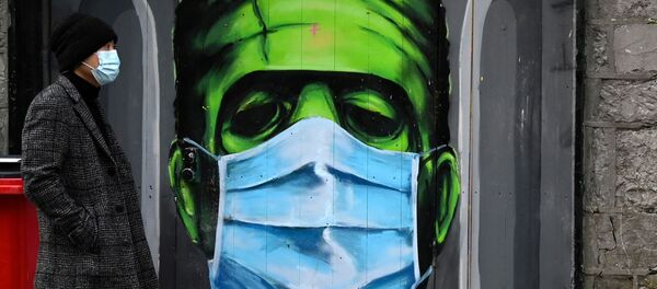 A man walks past a graffiti of a Frankenstein wearing a protective face mask on a doorway amid the spread of the coronavirus disease (COVID-19) pandemic, in Galway, Ireland, December 22, 2020 - Sputnik International