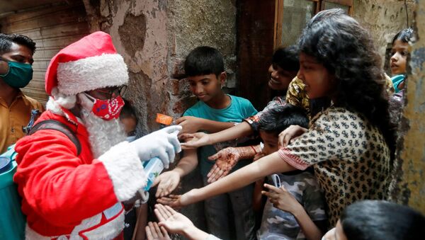 A man wearing a Santa Claus costume sanitizes children's hands inside a slum, amidst the spread of the coronavirus disease (COVID-19), in Mumbai, India, December 19, 2020 - Sputnik International