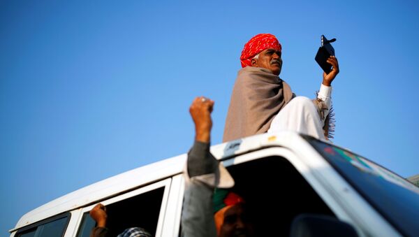 A farmer sits on a vehicle as others gesture at the site of a protest against new farm laws at a state border on a national highway in Shahjahanpur, in the desert state of Rajasthan, near New Delhi, India, December 26, 2020 - Sputnik International