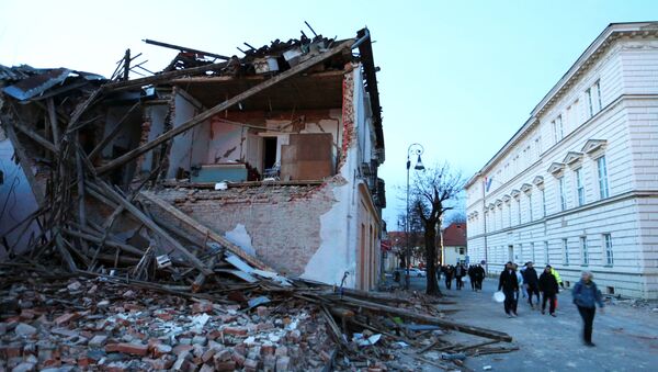 People walk past a collapsed building after an earthquake, in Petrinja, Croatia December 29, 2020.  - Sputnik International