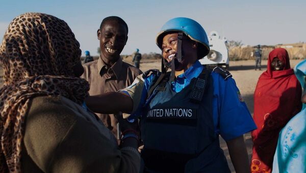 A UNAMID police officer interacts with women at a water point in Nifasha camp for internally displaced persons, north Darfur. - Sputnik International