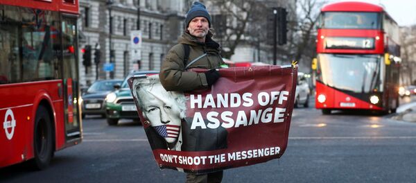 A man rides a skateboard holding a banner with an image of Julian Assange in London, Britain, December 30, 2020 - Sputnik International