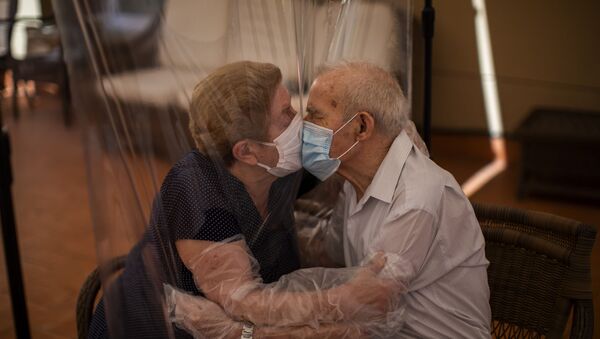 Agustina Cañamero, 81, and Pascual Pérez, 84, hug and kiss through a plastic film screen to avoid contracting the new coronavirus at a nursing home in Barcelona, Spain, Monday, June 22, 2020.  - Sputnik International