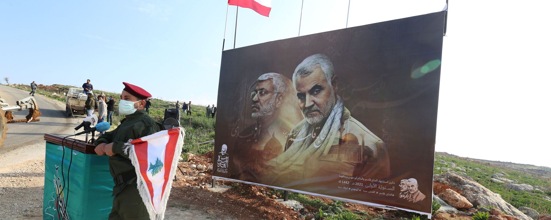 A member of Lebanon's Hezbollah holds a Lebanese flag as he stands in front of a picture depicting senior Iranian military commander General Qassem Soleimani and Iraqi militia commander Abu Mahdi al-Muhandis who were killed in a U.S. attack, during a ceremony marking the first anniversary of their killing, in the southern village of Khiam, Lebanon January 3, 2021. REUTERS/Aziz Taher - Sputnik International, 1920, 07.01.2022