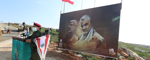A member of Lebanon's Hezbollah holds a Lebanese flag as he stands in front of a picture depicting senior Iranian military commander General Qassem Soleimani and Iraqi militia commander Abu Mahdi al-Muhandis who were killed in a U.S. attack, during a ceremony marking the first anniversary of their killing, in the southern village of Khiam, Lebanon January 3, 2021. REUTERS/Aziz Taher - Sputnik International