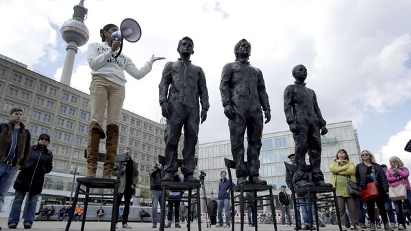A woman delivers a speech as she stands on a chair of the public art project Anything to Say? at the Alexander Square in Berlin, Germany, Friday, May 1, 2015. The sculpture of the Italian artist Davide Dormino shows the whistleblowers Chelsea Manning, Julian Assange and Edward Snowden, from right, to honour their courage. (AP Photo/Michael Sohn) - Sputnik International