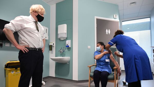 Britain's Prime Minister Boris Johnson looks on as Jennifer Dumasi receives the Oxford University/AstraZeneca COVID-19 vaccine during his visit at the Chase Farm Hospital, in north London, Britain January 4, 2021. - Sputnik International