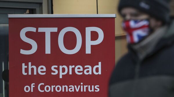 A man wearing a British union flag face mask walks past a coronavirus advice sign outside a bank in Glasgow the morning after stricter lockdown measures came into force for Scotland, Tuesday Jan. 5, 2021.  Further measures were put in place Tuesday as part of lockdown restrictions in a bid to halt the spread of the coronavirus. - Sputnik International
