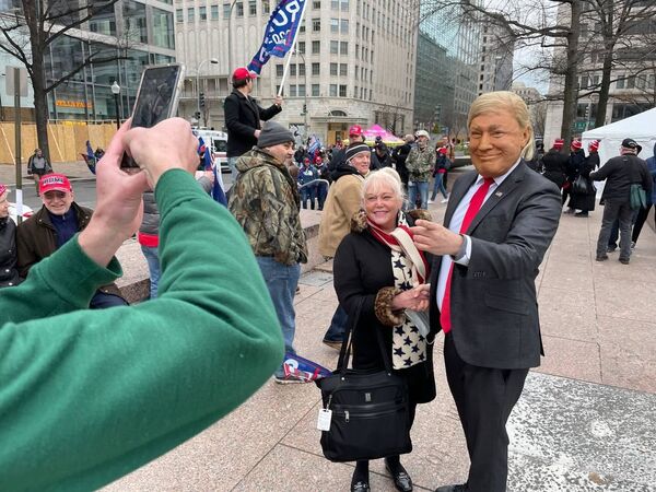 A demonstrator takes a selfie with a person wearing a Trump mask during a rally in Washington DC.  - Sputnik International