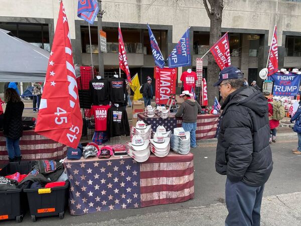 A man looks at caps and hats with pro-Trump slogans during a rally in DC.  - Sputnik International