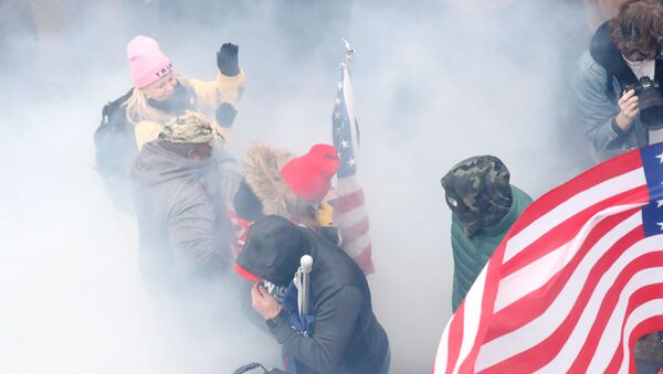 Pro-Trump protesters react amidst a cloud of tear gas during clashes with Capitol police at a rally to contest the certification of the 2020 US presidential election results by the US Congress, at the US Capitol Building in Washington, US, January 6, 2021. REUTERS/Shannon Stapleton - Sputnik International