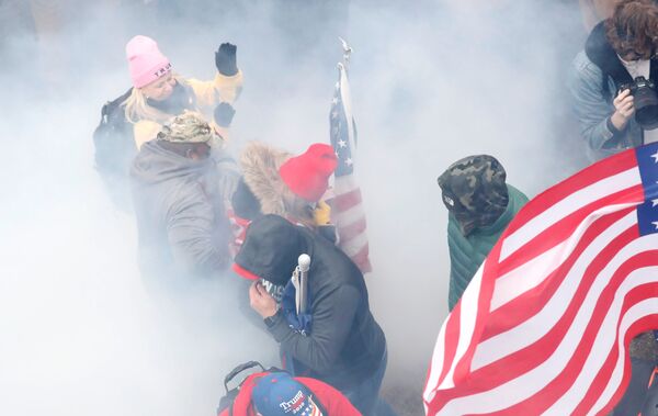 Pro-Trump protesters react amidst a cloud of tear gas during clashes with Capitol police at a rally to contest the certification of the 2020 US presidential election results by the US Congress, at the US Capitol Building in Washington, US, 6 January 2021. REUTERS/Shannon Stapleton - Sputnik International