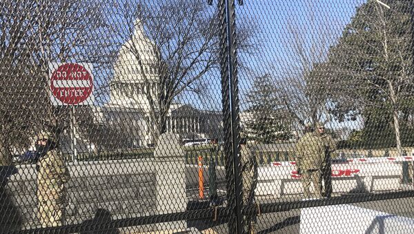 Members of the National Guard stand inside anti-scaling fencing that surrounds the Capitol, Sunday, Jan. 10, 2021, in Washington - Sputnik International