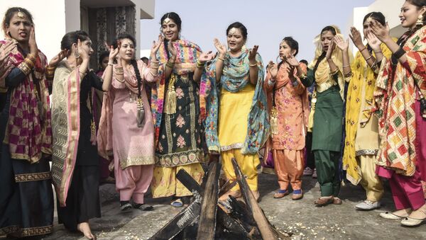 Students in traditional Punjabi dress perform the giddha folk dance around a bonfire on the eve of the Lohri festival in Amritsar on 12 January 2021. - Sputnik International