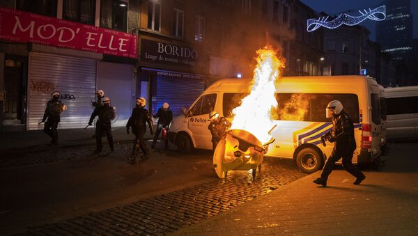 Police officers try to extinguish a fire set in a dumpster in the Belgium capital, Brussels, Wednesday, Jan. 13, 2021, at the end of a protest asking for authorities to shed light on the circumstances surrounding the death of a 23-year-old Black man who was detained by police last week in Brussels. The demonstration in downtown Brussels was largely peaceful but was marred by incidents sparked by rioters who threw projectiles at police forces and set fires before it was dispersed. - Sputnik International